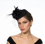 Black pillbox fascinator hat with a flower detail and birdcage veil attached to a clip