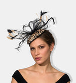 A woman wearing a fascinator hat with a leopard print base and black feather accents photography model