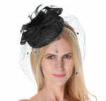 Woman wearing a black pillbox fascinator with a bow, feathers and a birdcage veil across her face