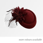 Burgundy pillbox fascinator with a flower, feathers, bead detailing and black net veil